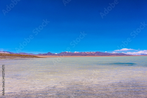 Blue lake and the mountains with snow on top at Salar de Chalviri  Bol  via 