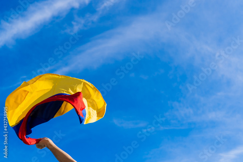 hand in fist at a protest in Colombia holding a flag against a blue sky background
