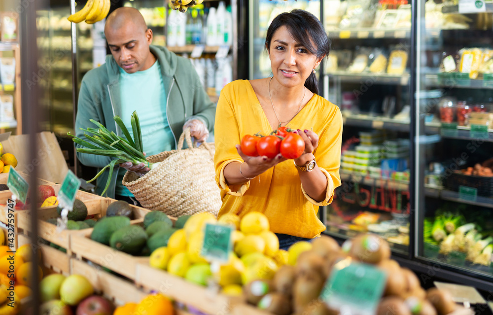 Obraz premium Married couple choosing ripe tomatoes at grocery store