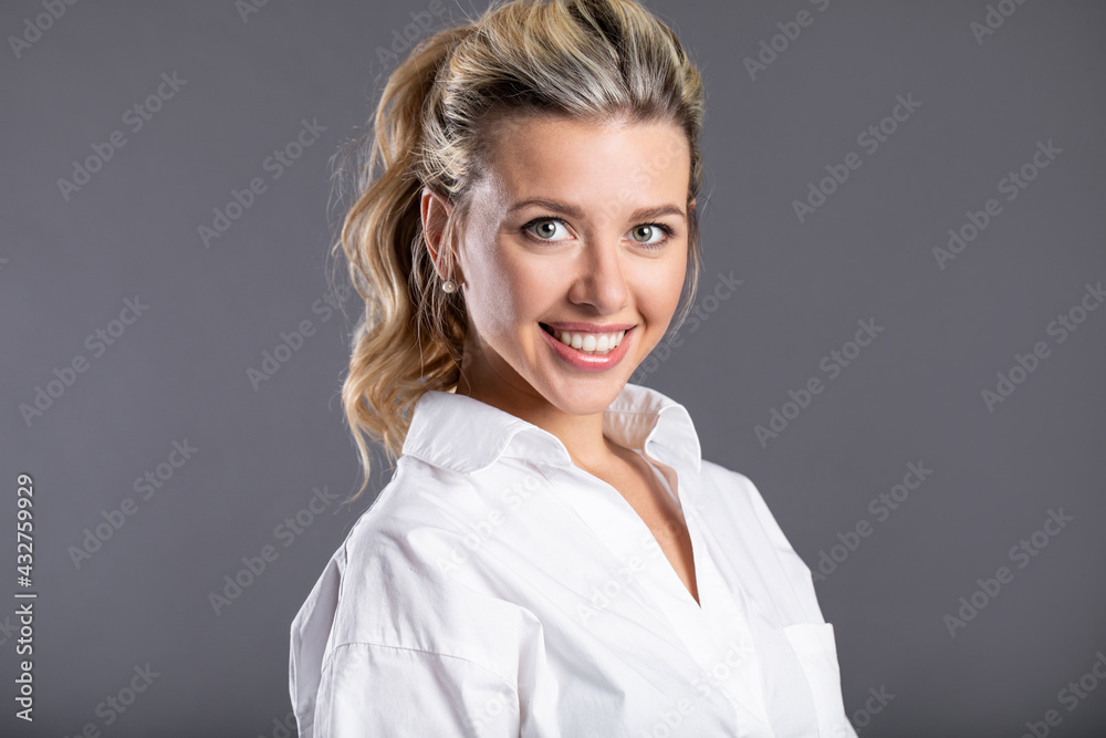 Close-up portrait of a European woman. Beautiful smiling blonde girl on gray background Close-up portrait of a European woman. Beautiful smiling blonde girl on gray background