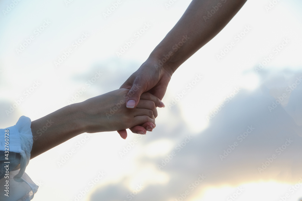 One woman was reaching out to help pull another woman's hand. To help her come up from below. Is a good team work.Both white women One woman was reaching out to help pull another woman's hand. To help her come up from below. Is a good team work.Both white women
