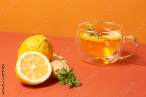 Ginger tea with mint and lemon. Healthy drink. Crystal cup on bright background. Selective focus.