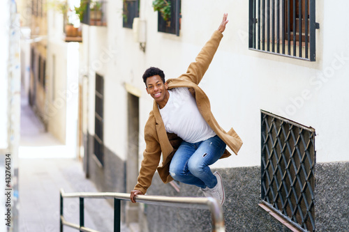 Cuban man jumping for joy over a handrail in the street.