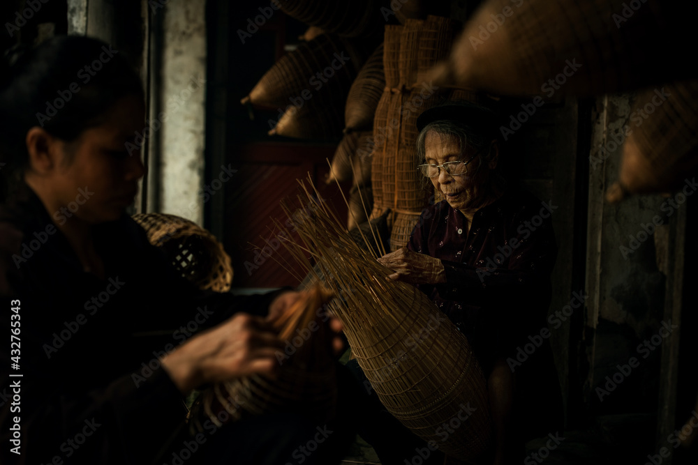 Obraz premium Craftsman making bamboo fish trap at old village, Hung Yen, Vietnam