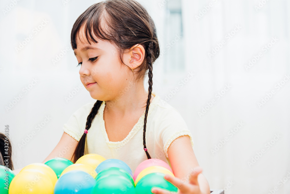 Beautiful baby kids girl kindergarten playing colorful ball at interior room home Beautiful baby kids girl kindergarten playing colorful ball at interior room home