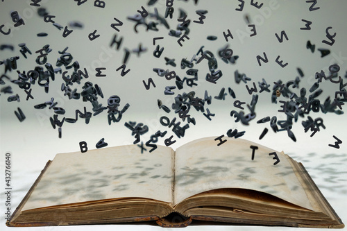 Fotografie Letters of the alphabet in levitation in the air over the open book
