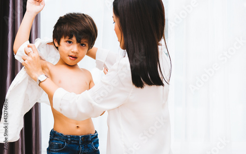 Quadro em tela Asian happy beautiful mother helping to get dressed clothes on her boy kid in ho