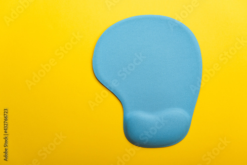 Top view flat lay of blue pad or mousepad for computer mouse modern design isolated on a yellow background and copy space photo
