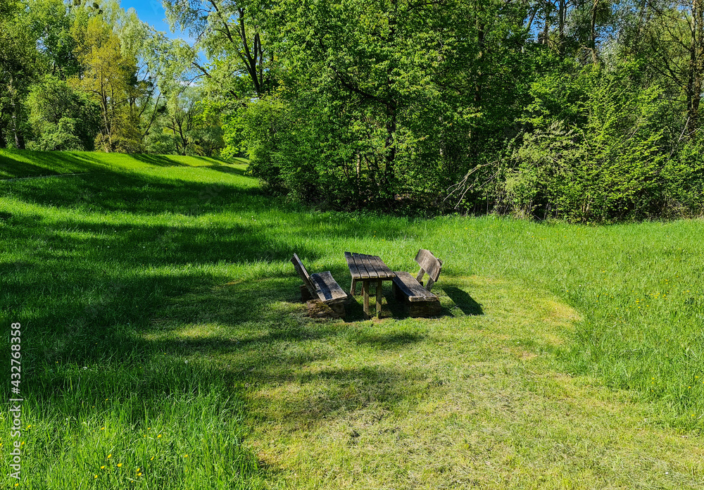 Rustic wooden picnic table with benches in the middle of a green meadow on the edge of the forest. Rustic wooden picnic table with benches in the middle of a green meadow on the edge of the forest.
