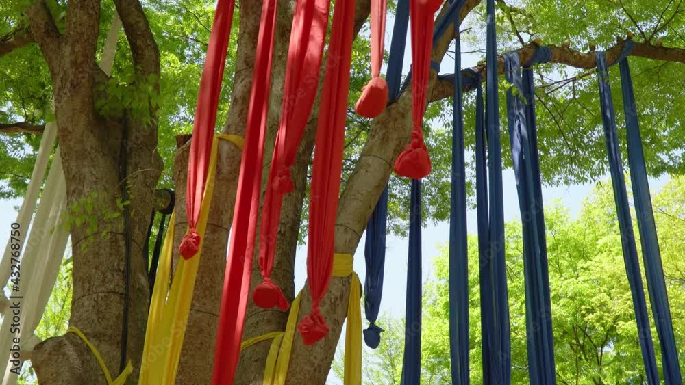 Seonangdang, holy stone cairns or trees dedicated to the patron deity of a village. Multicolored Ribbons with stones Hanging On Branches Of A Tree At Korean Folk Village Seonangdang, holy stone cairns or trees dedicated to the patron deity of a village. Multicolored Ribbons with stones Hanging On Branches Of A Tree At Korean Folk Village