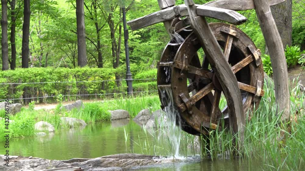 Old Wooden Water Wheel At Namsan Park With Green Forest At Namsan Mountain In Seoul, South Korea. - wide shot Old Wooden Water Wheel At Namsan Park With Green Forest At Namsan Mountain In Seoul, South Korea. - wide shot