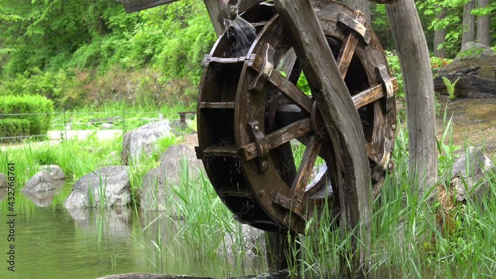 Wooden Water Wheel placed near small lake At Namsan Park With Green Forest At Namsan Mountain In Seoul, South Korea. - wide shot Wooden Water Wheel placed near small lake At Namsan Park With Green Forest At Namsan Mountain In Seoul, South Korea. - wide shot