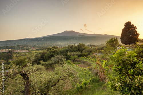 Sicilian rural landscape with Etna volcano eruption at sunset in Sicily