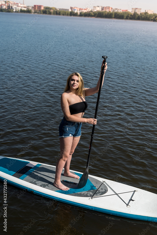 Slim girl relaxed lying on SUP board relaxed in dark blue water