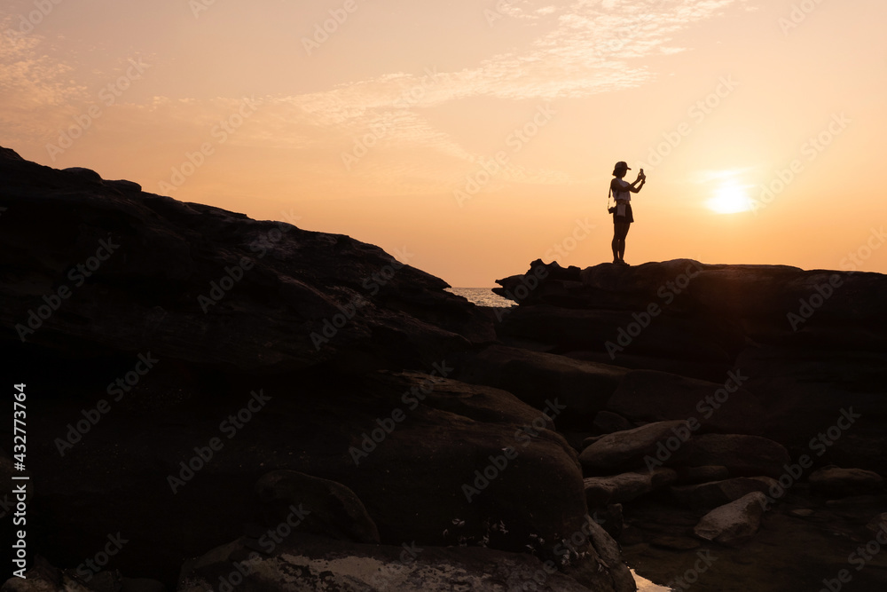 Tourist stand on rock cape and taking sunset image on tropical island. Koh Kood - Thailand