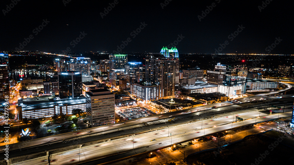 Aerial cityscape of downtown Orlando at night with the 408 expressway in the foreground.