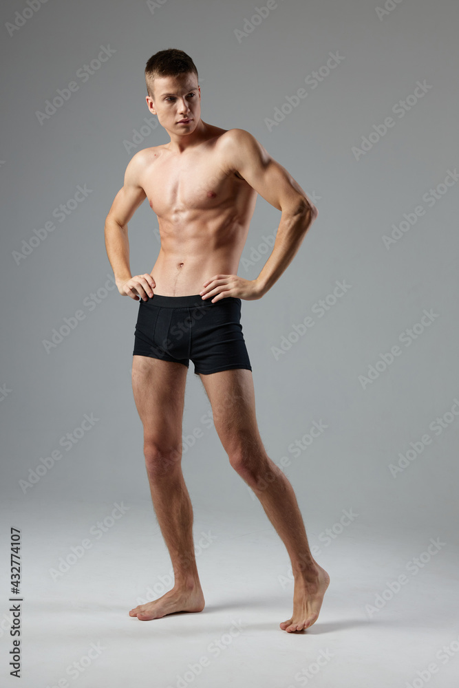 naked man in black panties on a gray background pumped up muscles