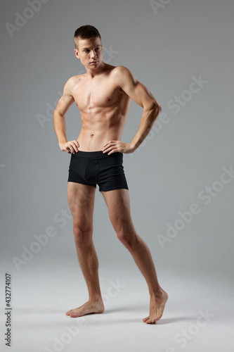 naked man in black panties on a gray background pumped up muscles