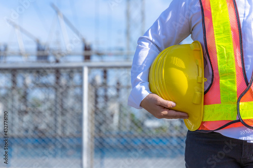 Female engineer holding a yellow helmet by her side at the main power station.