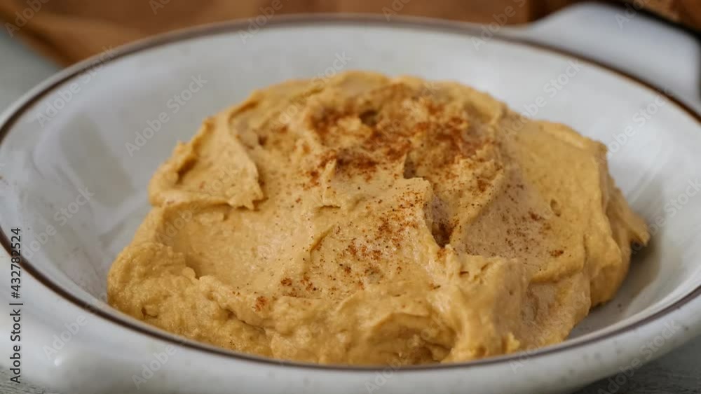 Sprinkling paprika onto a bowl of hummus slow motion Sprinkling paprika onto a bowl of hummus slow motion
