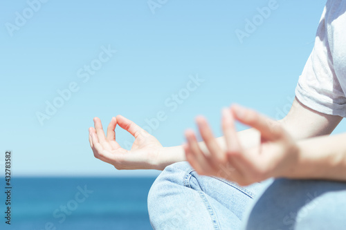 Closeup of a woman's hands meditating outdoors at the seaside.