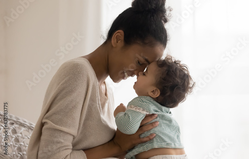 Fotografi Happy young African American mom hug cuddle with little baby kid daughter at home