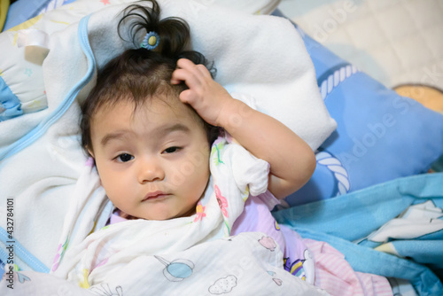 Cute little Asian baby girl wrapped in a blanket just woke up looking at camera , baby expression concept