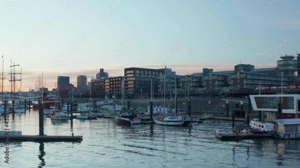 Low aerial dolly view of anchored boats and sailboats in Hamburg harbor at sunset Low aerial dolly view of anchored boats and sailboats in Hamburg harbor at sunset
