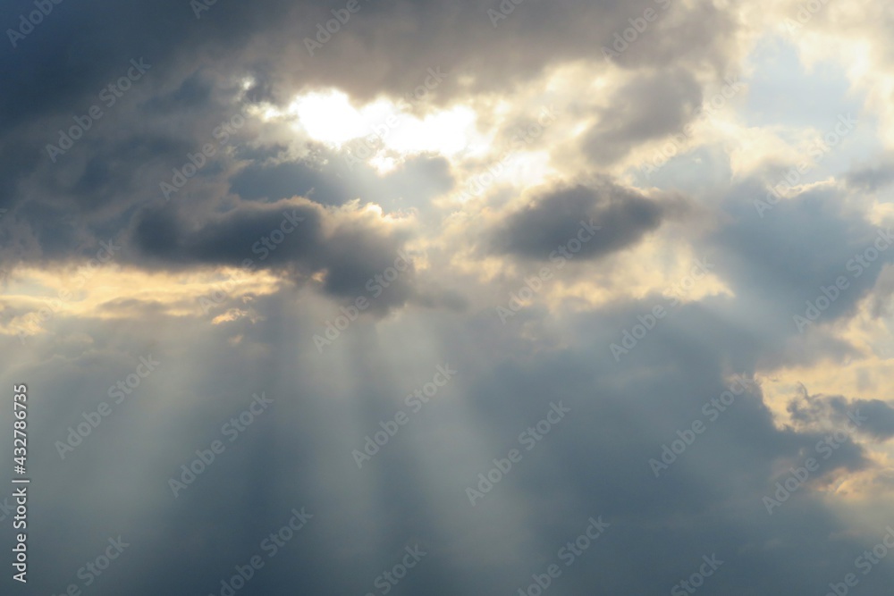 Sun rays shine through dark clouds at sunset, natural background Sun rays shine through dark clouds at sunset, natural background