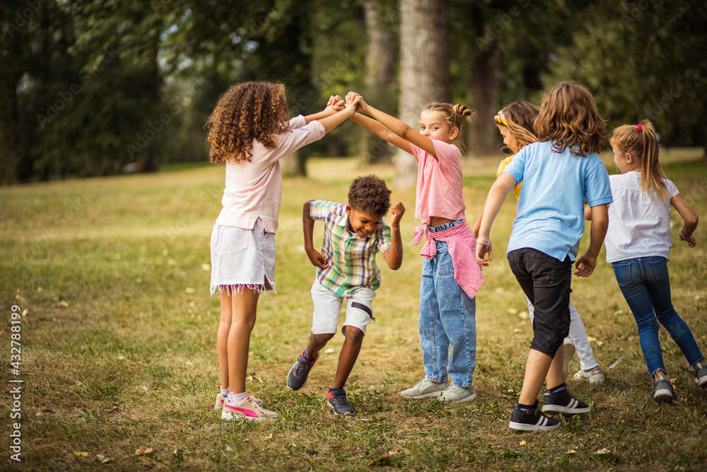 Obraz premium Large group of school kids having fun in nature. Carefree children playing in the park.