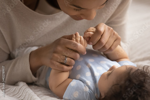 Billede på lærred Close up of young African American mother cuddle play with little newborn baby girl child at home together