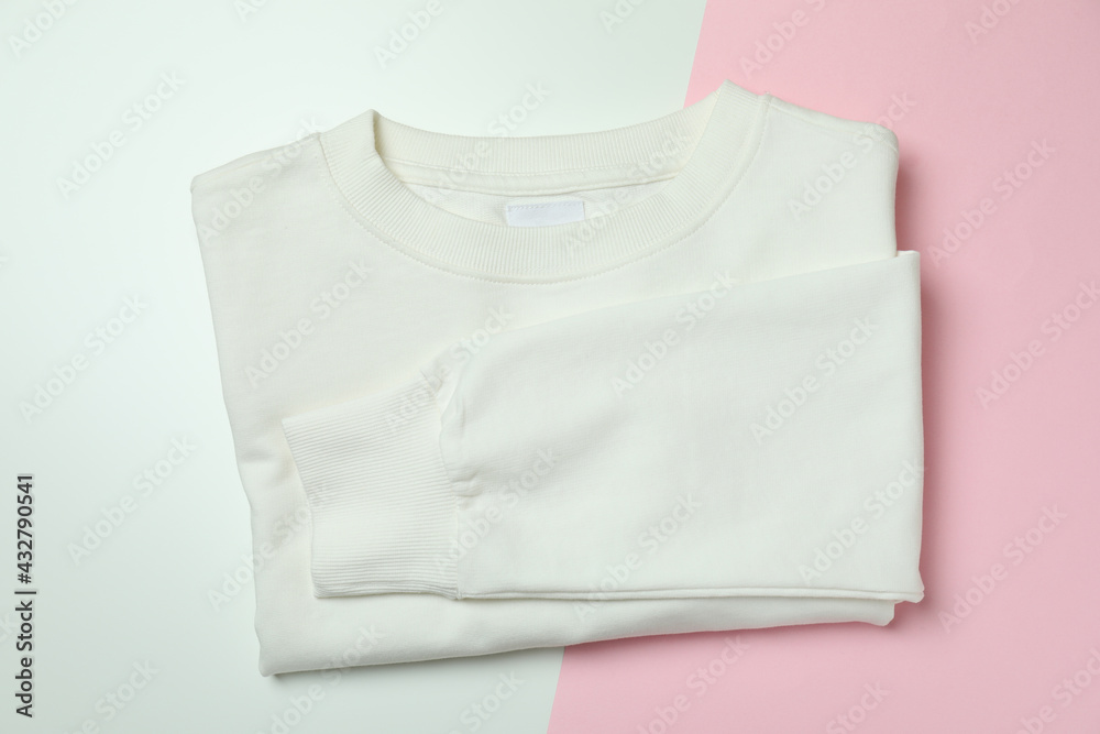 Folded white sweatshirt on two tone background Folded white sweatshirt on two tone background