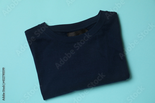 Folded t-shirt on blue background, top view