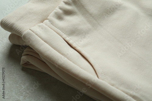 Folded sweatpants on white textured background, close up photo