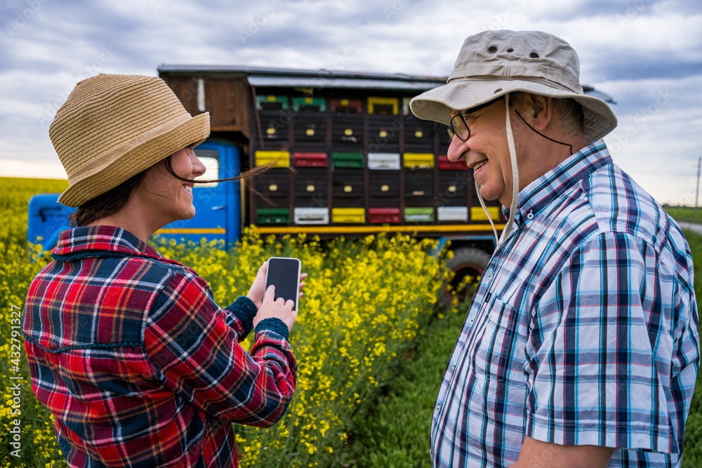 Proud two generations beekeepers are standing in front of their truck with beehives. Proud two generations beekeepers are standing in front of their truck with beehives.