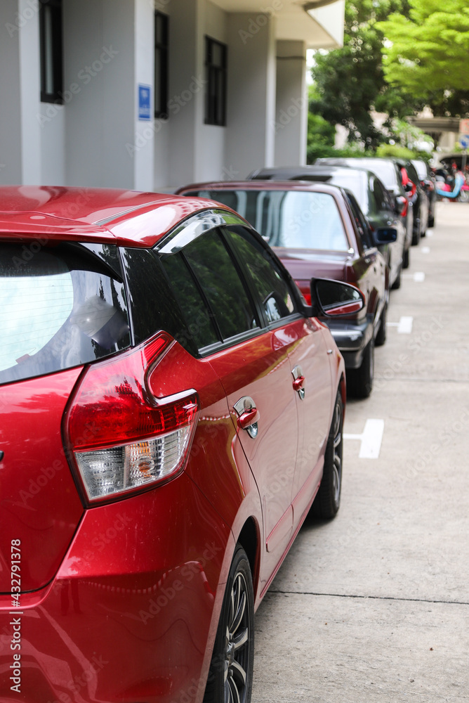 Closeup of rear, back side of red car with  other cars parking in outdoor parking area. Vertical view.