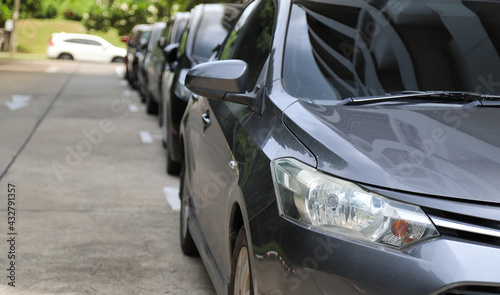 Closeup of front side of dark gray car with  other cars parking in outdoor parking area. © Amphon