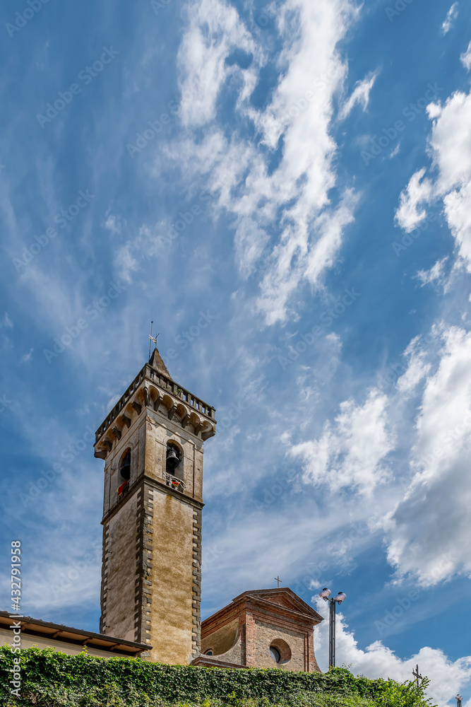 The bell tower and part of the facade of the Santa Croce church in the historic center of Vinci, Florence, Italy, against a dramatic sky