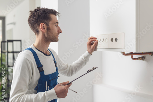 Professional plumber checking a boiler control panel photo