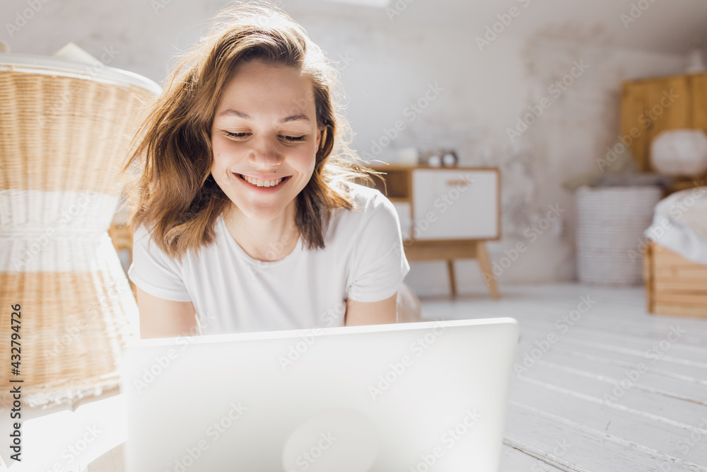 Attractive African-American girl uses laptop and smiles while sitting on the floor Attractive African-American girl uses laptop and smiles while sitting on the floor