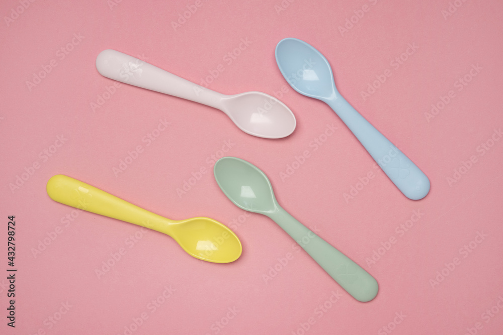 Kid spoons in different colors laid on sweet pink pastel background, a set of colorful spoons, pastel palette spoons Kid spoons in different colors laid on sweet pink pastel background, a set of colorful spoons, pastel palette spoons