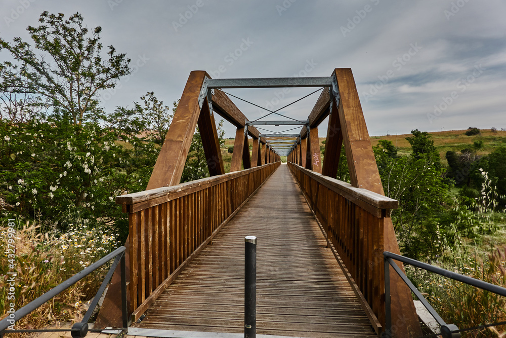 Wooden pedestrian bridge over the Soto stream on the Guadarrama River Greenway. Madrid's community. Spain
