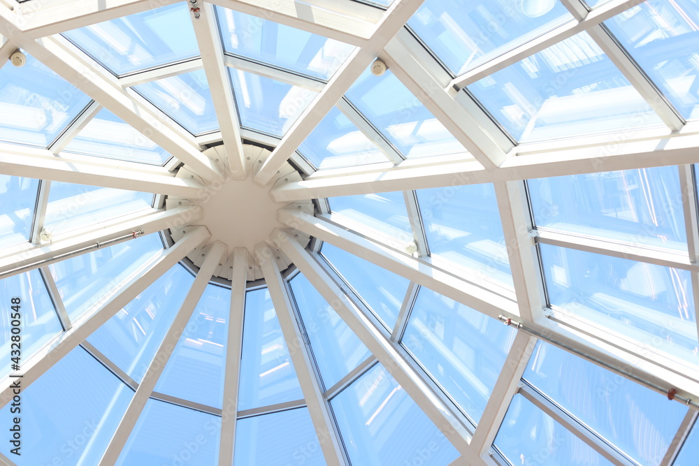 Glass dome with white structure in shopping mall in sunny day.