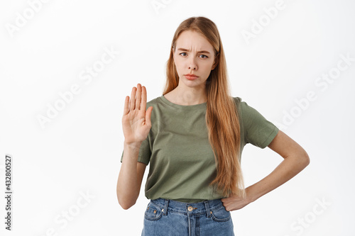 Stop, she says no. Serious displeased woman showing raised palm to block, disapprove something, prohibit and reject, standing against white background
