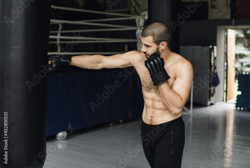 Fighter Practicing Some Kicks With Punching Bag. Kick, punching bag on dark background. Black punching bag weighs at the gym