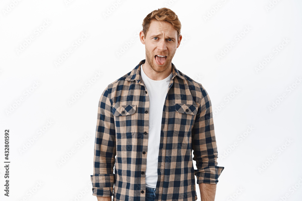 Handsome redhead man acting childish, adult ginger guy showing tongue and grimacing disgusted, hate bad taste, complaining, dislike something awful, standing over white background Handsome redhead man acting childish, adult ginger guy showing tongue and grimacing disgusted, hate bad taste, complaining, dislike something awful, standing over white background