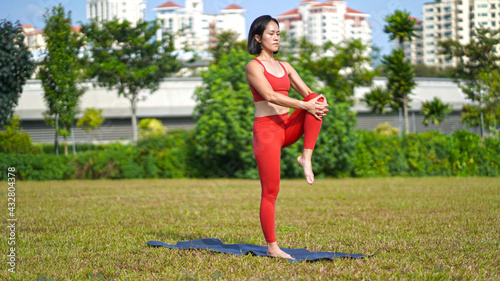 asian chinese female lady yogi practise yoga stretches poses in the park in beautiful weather