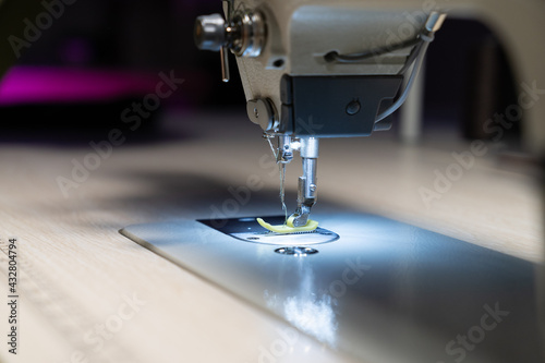 Closeup of modern sewing machine needle and fabric. Tailor or professional seamstress workplace. Garment industry manufacture. Equipment for dressmaking hobby or tailoring business occupation concept
