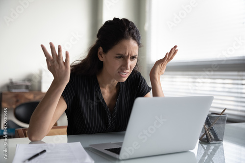 What is wrong. Anxious angry hispanic female splash hands unable to access database on laptop forgetting password having weak wifi signal. Mad shocked young woman worker losing job result on broken pc photo