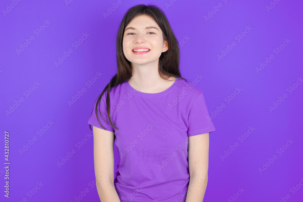 young beautiful Caucasian girl wearing purple T-shirt over purple background with nice beaming smile pleased expression. Positive emotions concept young beautiful Caucasian girl wearing purple T-shirt over purple background with nice beaming smile pleased expression. Positive emotions concept
